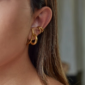 Three minimalist gold hoop earrings set on model ear for a modern jewelry look