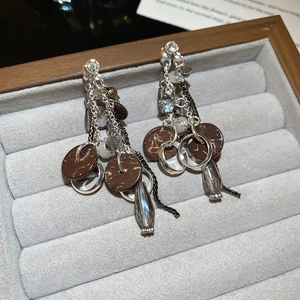 Macro detail of silver needle drop earrings with crystal tassels and brown wooden discs