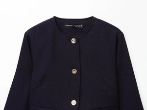 Gros plan détaillé du col du blazer bleu marine avec boutons dorés et texture du tissu