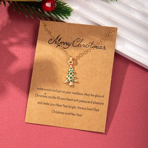 Close-up of golden Christmas tree necklace with red and green stones on a festive card