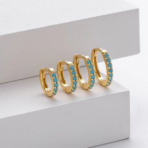 Detailed view of four golden silver hoop earrings with turquoise stone inlays in varied sizes