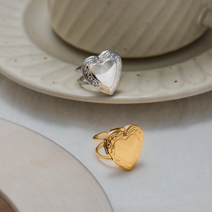 Dettaglio di anelli a medaglione a cuore in oro 18k con rilievo e fascia regolabile