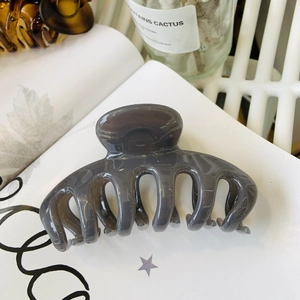 Detail view of large dark grey translucent hair claw clip on white magazine background