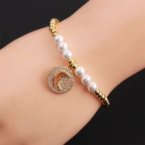 Detail of beaded bracelet with gold beads, white pearls and a sparkling moon pendant