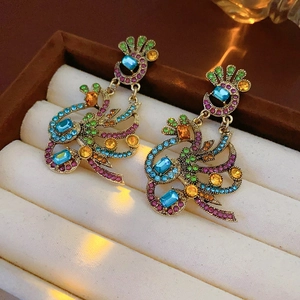 Close-up of vintage gold peacock earrings with colorful crystals in velvet box