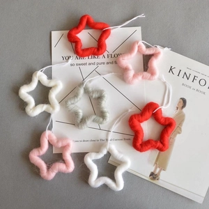 Detailed texture of colorful felt star ornaments with hanging ropes on a minimalist background