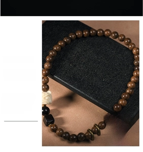 Detail of sandalwood beads with ornate beast carving on a professional display