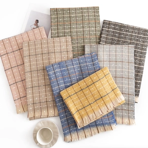 Maillard style plaid tassel scarves stacked on white background with coffee and magazine