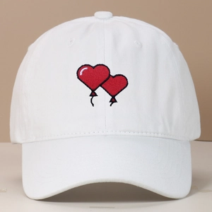 Close-up of red heart balloon embroidery on a white washed cotton baseball cap