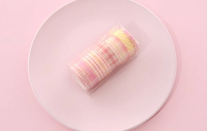 Detail of pink and yellow plaid washi tape set in transparent packaging on a round plate