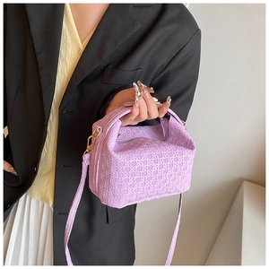 Detail of purple woven texture pillow bag with top handle and adjustable shoulder strap