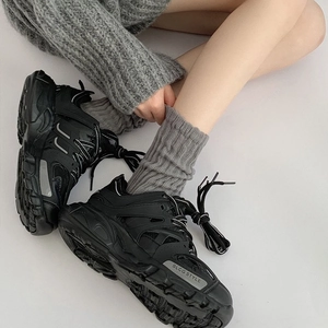 Detail of black chunky sneakers with mesh panels and grey knitted mid-calf socks