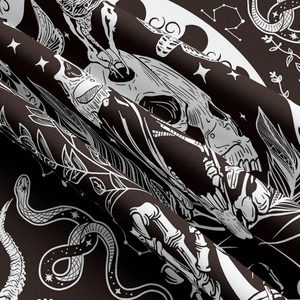 Macro shot of gothic tapestry fabric featuring white skull, snake, and astrology patterns