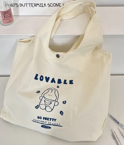 Detail of cute blue rabbit print on cream canvas tote bag with metal button closure
