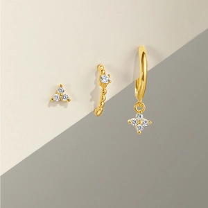 Detailed close-up of three gold 925 silver earrings with sparkling zircon gemstones