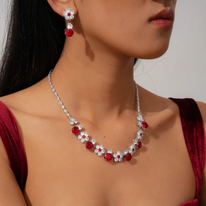 Detailed close-up of floral jewelry set with red gemstones and zircons on red velvet