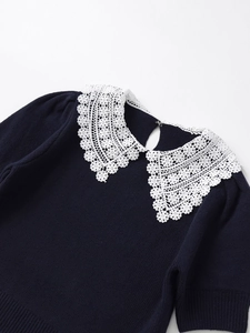 Close-up of elegant navy knit top featuring white lace Peter Pan collar with back clasp