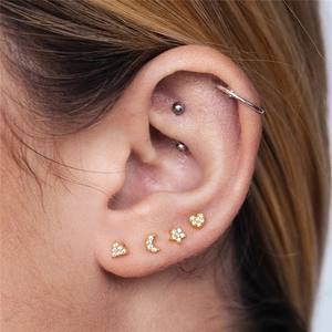 Detail shot of gold-plated heart, star and moon ear studs set with sparkling crystals