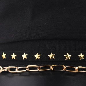 Detail of black PU beret featuring gold star rivets and chunky metal chain decoration