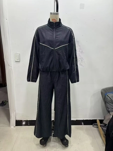 Détail d'un survêtement en denim foncé avec des bandes latérales blanches sur un mannequin