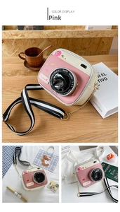 Detail view of pink and white camera-shaped shoulder bag with striped woven chain strap