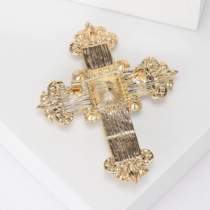 Back view of a gold vintage cross brooch showing the metal base texture and pin buckle