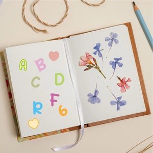 Close-up of colorful alphabet stickers on a leather notebook with floral accents