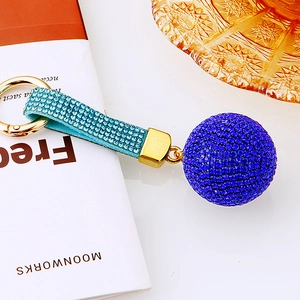 Dettaglio macro di un ciondolo a sfera con strass blu, anello dorato e cinturino blu