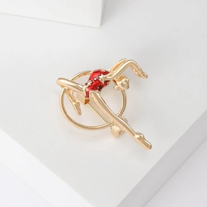 Detail of golden gymnast brooch with red enamel accent on a clean white background