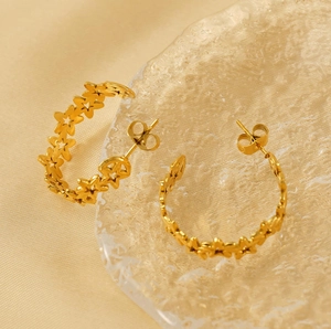 Close-up of golden hollow star C-shaped earrings on elegant champagne silk background