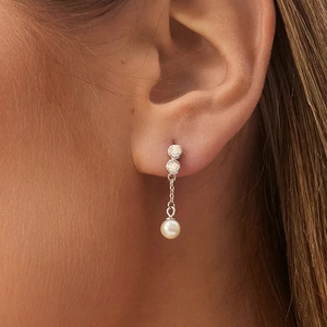 Detailed close-up of a silver chain drop earring with white pearl pendant on model