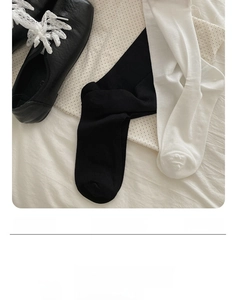 Detail view of thin mulberry silk socks paired with black leather shoes and white lace laces
