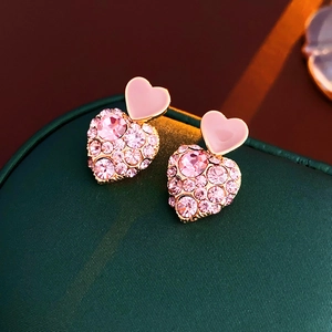 Macro shot of pink heart earrings with rhinestones on a dark green jewelry box