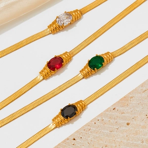 Detailed view of four gold snake chain necklaces with white, red, green and black gemstones