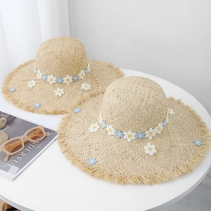 Handwoven raffia straw hat with embroidered daisies and frayed edges for summer sun protection