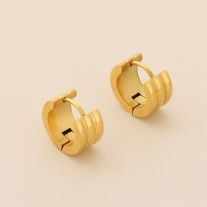 Close-up of 18K gold ribbed huggie hoop earrings with matte brushed metal texture
