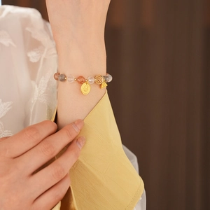Close-up of crystal moonstone beaded bracelet with gold charms on a female wrist