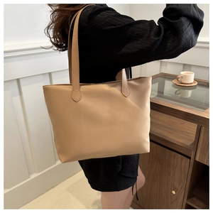 Detailed shoulder view of a large khaki tote bag styled with a minimalist casual outfit