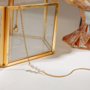 Detail of a gold fine chain anklet with three white pearls and a lobster clasp