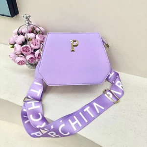 Detail of purple trapezoid tote bag with gold P emblem and branded wide shoulder strap
