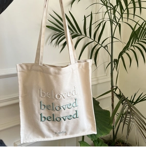 Close-up of embroidered green gradient beloved text on cream canvas tote bag