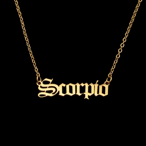 Detailed close-up of golden Scorpio necklace with Gothic letter pendant on black background