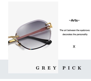 Close-up of frameless sunglasses with grey gradient lenses and golden baroque metal temples