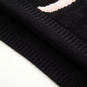 Detailed macro view of black knit texture with pink floral pattern and ribbed edge
