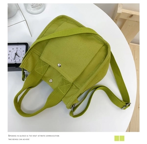 Detailed top view of a green canvas tote bag featuring metal snap and adjustable strap