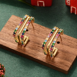 Detail of C-shaped gold-plated earrings with colorful zircon stones on wooden stand