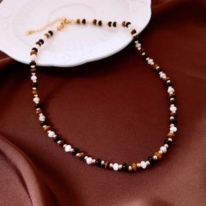 Detail of multi-layer beaded necklace with pearls and tiger eye on silk fabric