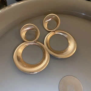 Macro shot of gold double circular earrings with detailed radial texture on metal surface