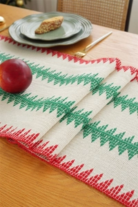 Detail of Christmas table runner with red geometric patterns and green pine tree weaving