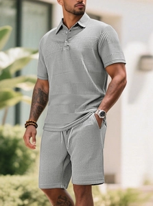 Detail of grey-blue men's knit set showing waffle texture, polo collar and drawstring shorts